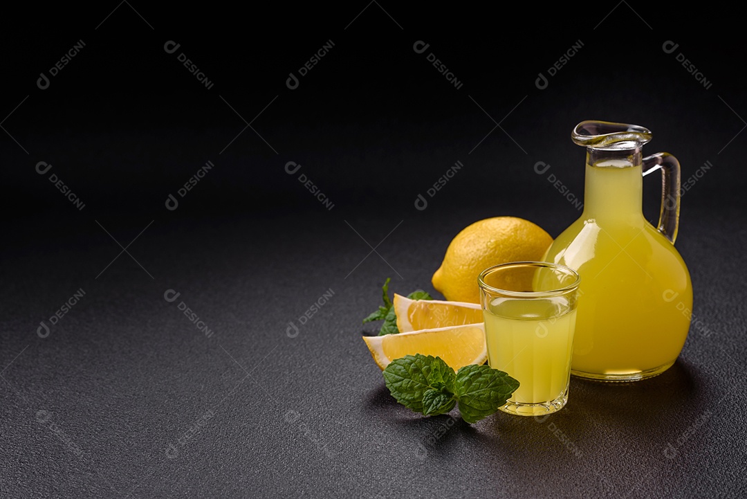 Bebida alcoólica limoncello amarelo em um copo pequeno sobre um fundo escuro de concreto
