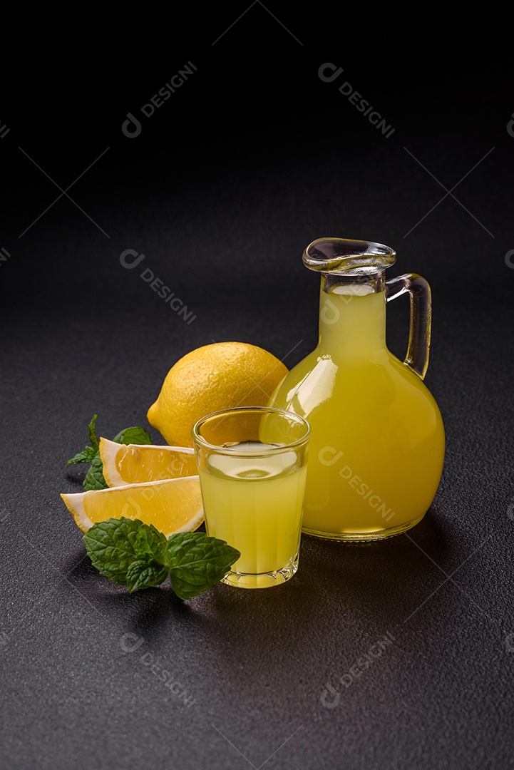 Bebida alcoólica limoncello amarelo em um copo pequeno sobre um fundo escuro de concreto