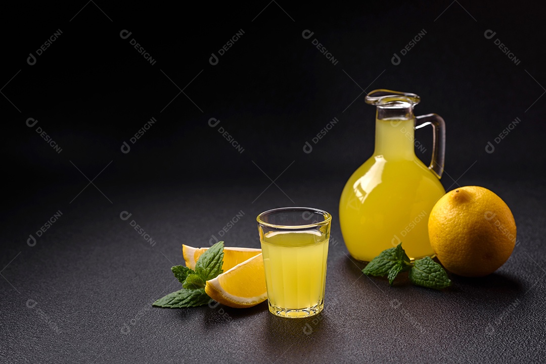 Bebida alcoólica limoncello amarelo em um copo pequeno sobre um fundo escuro de concreto