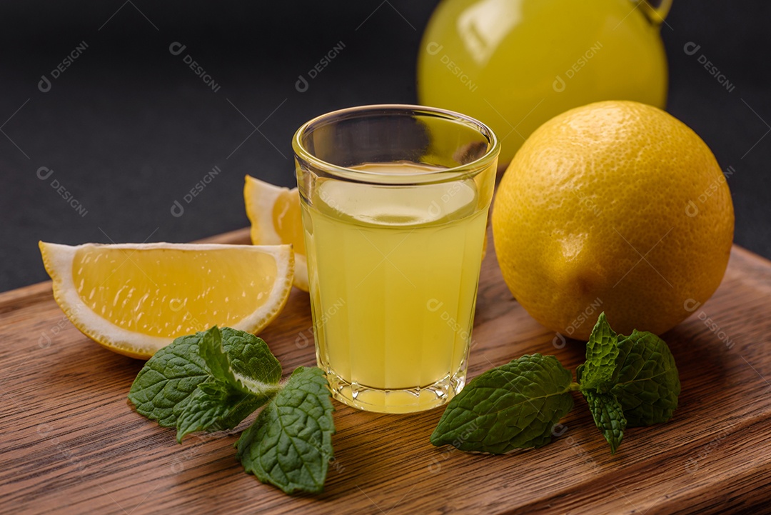 Bebida alcoólica limoncello amarelo em um copo pequeno sobre um fundo escuro de concret
