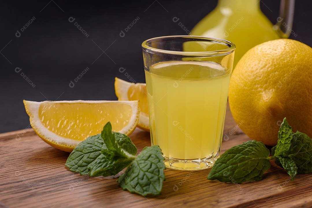 Bebida alcoólica limoncello amarelo em um copo pequeno sobre um fundo escuro de concreto
