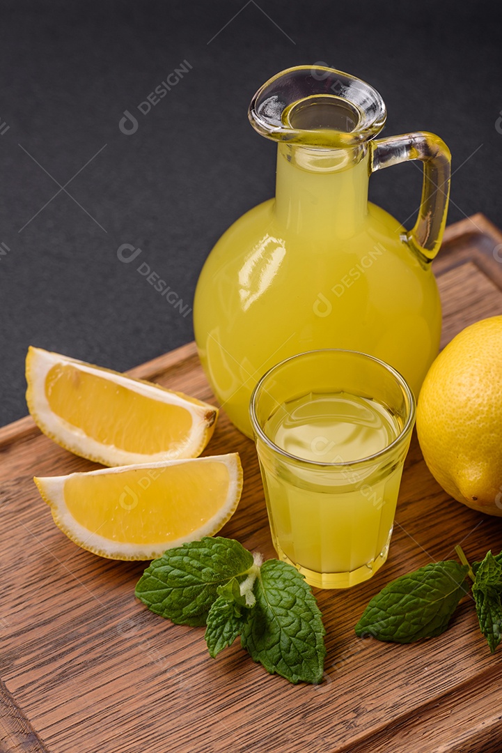 Bebida alcoólica limoncello amarelo em um copo pequeno sobre um fundo escuro de concreto