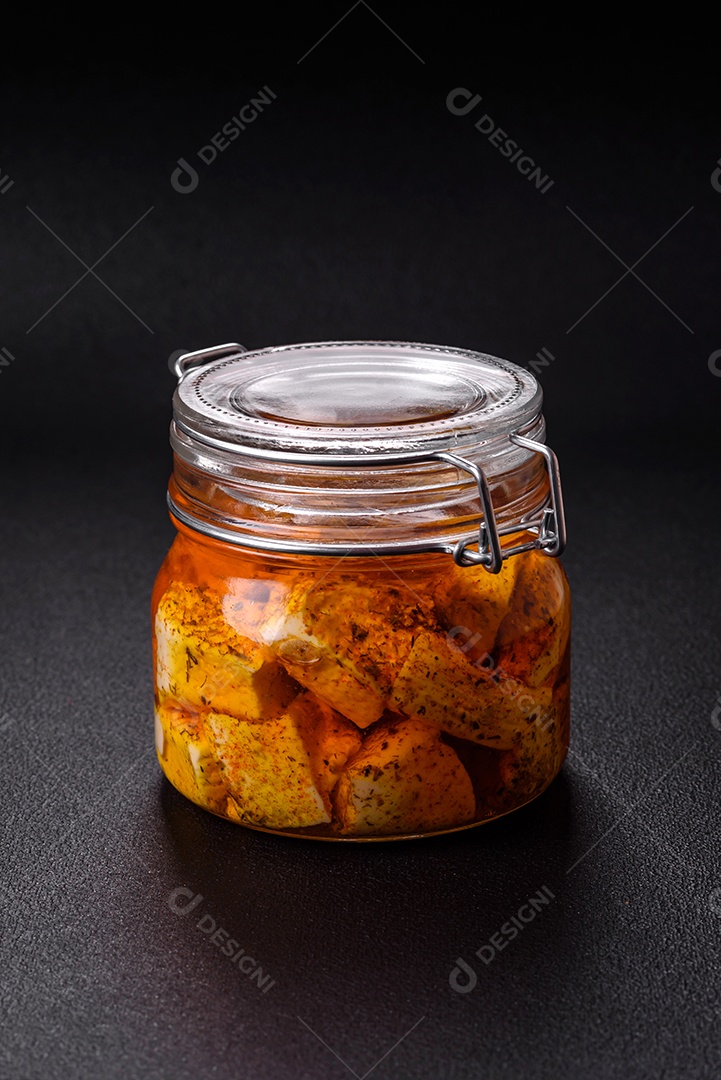 Delicioso queijo feta branco macio com sal, especiarias e ervas sobre um fundo escuro de concreto. Ingredientes para pratos mediterrâneos