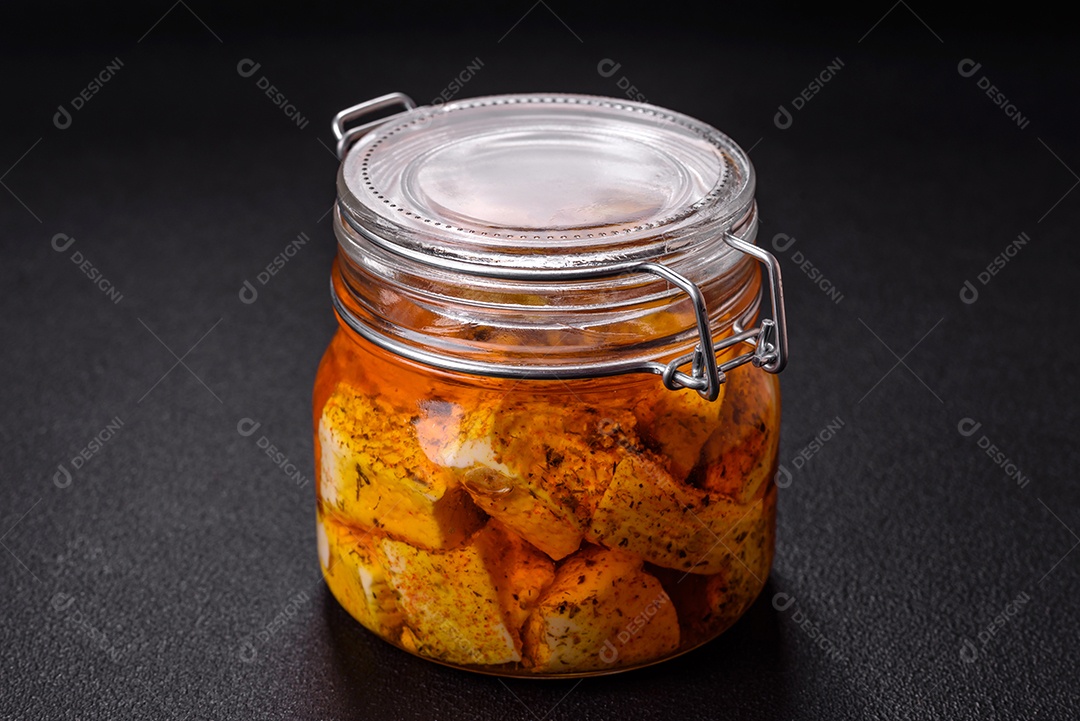 Delicioso queijo feta branco macio com sal, especiarias e ervas sobre um fundo escuro de concreto. Ingredientes para pratos mediterrâneos