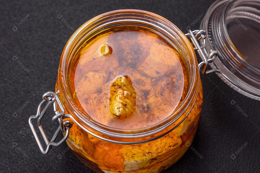 Delicioso queijo feta branco macio com sal, especiarias e ervas sobre um fundo escuro de concreto. Ingredientes para pratos mediterrâneos