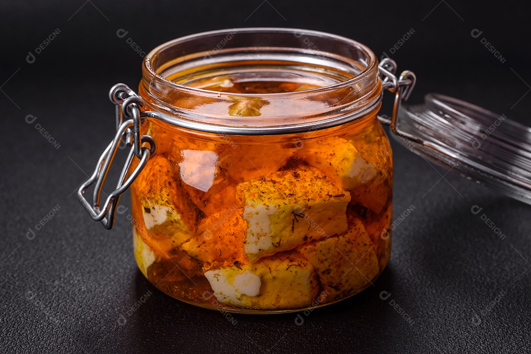 Delicioso queijo feta branco macio com sal, especiarias e ervas sobre um fundo escuro de concreto. Ingredientes para pratos mediterrâneos