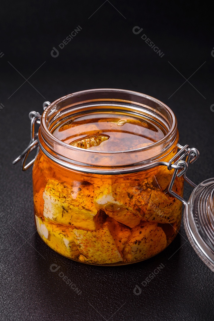 Delicioso queijo feta branco macio com sal, especiarias e ervas sobre um fundo escuro de concreto. Ingredientes para pratos mediterrâneos