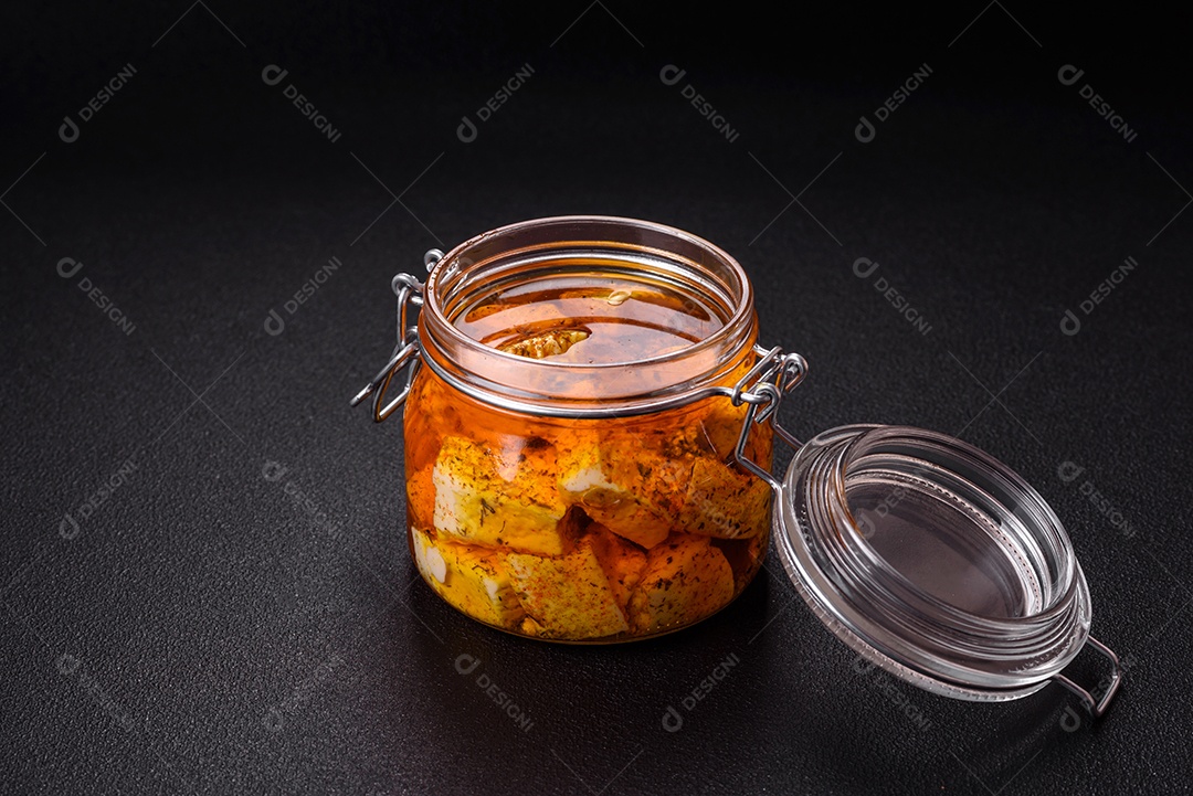 Delicioso queijo feta branco macio com sal, especiarias e ervas sobre um fundo escuro de concreto. Ingredientes para pratos mediterrâneos