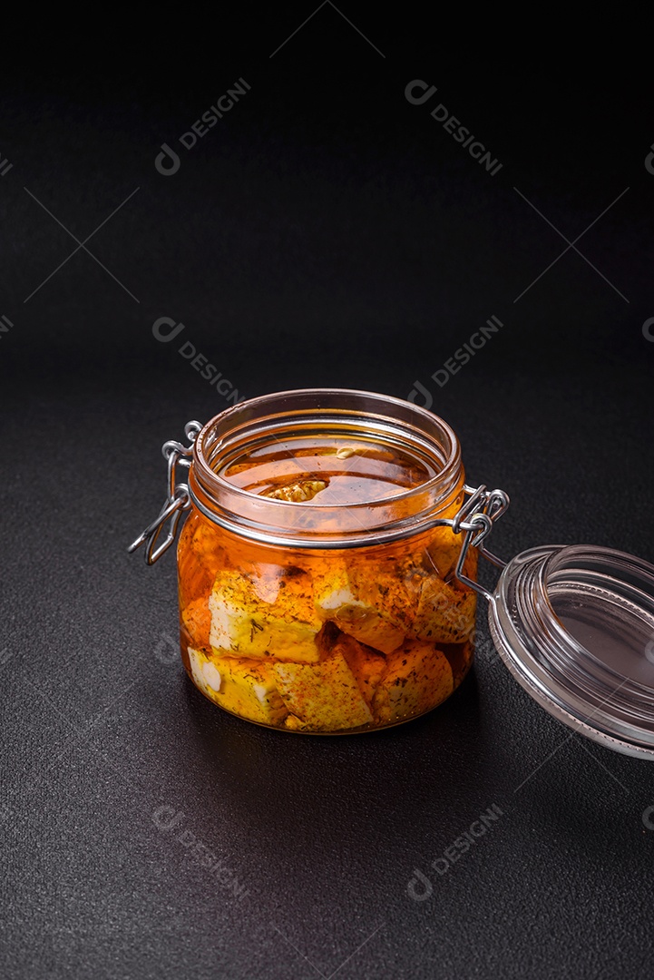 Delicioso queijo feta branco macio com sal, especiarias e ervas sobre um fundo escuro de concreto. Ingredientes para pratos mediterrâneos