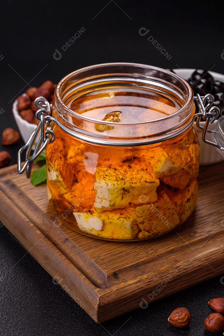 Delicioso queijo feta branco macio com sal, especiarias e ervas sobre um fundo escuro de concreto. Ingredientes para pratos mediterrâneos