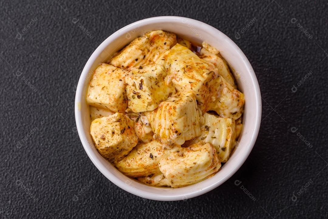 Delicioso queijo feta branco macio com sal, especiarias e ervas sobre um fundo escuro de concreto. Ingredientes para pratos mediterrâneos