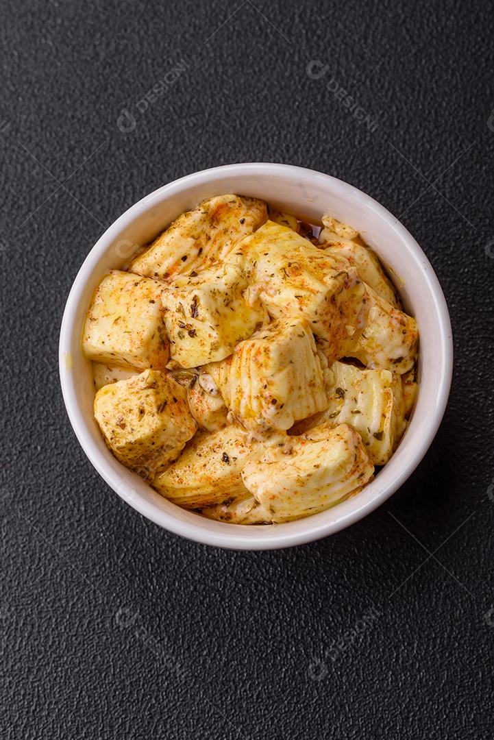 Delicioso queijo feta branco macio com sal, especiarias e ervas sobre um fundo escuro de concreto. Ingredientes para pratos mediterrâneos