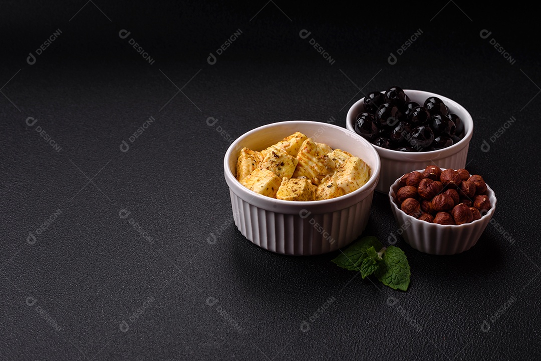 Delicioso queijo feta branco macio com sal, especiarias e ervas sobre um fundo escuro de concreto. Ingredientes para pratos mediterrâneos
