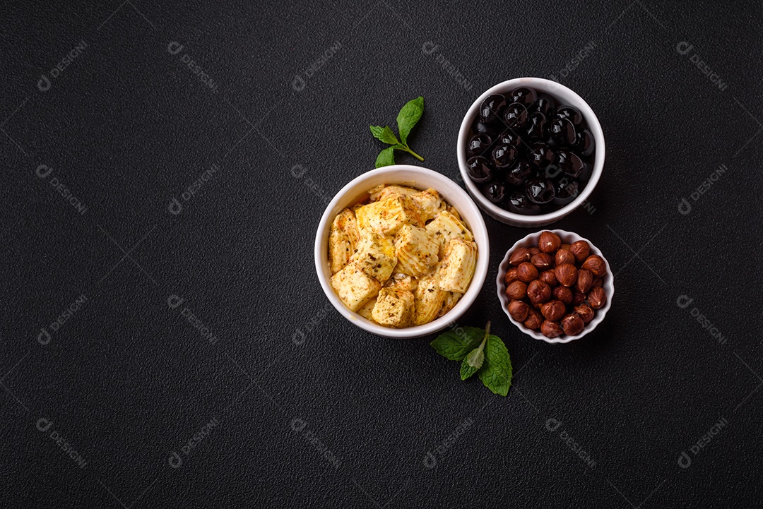 Delicioso queijo feta branco macio com sal, especiarias e ervas sobre um fundo escuro de concreto. Ingredientes para pratos mediterrâneos