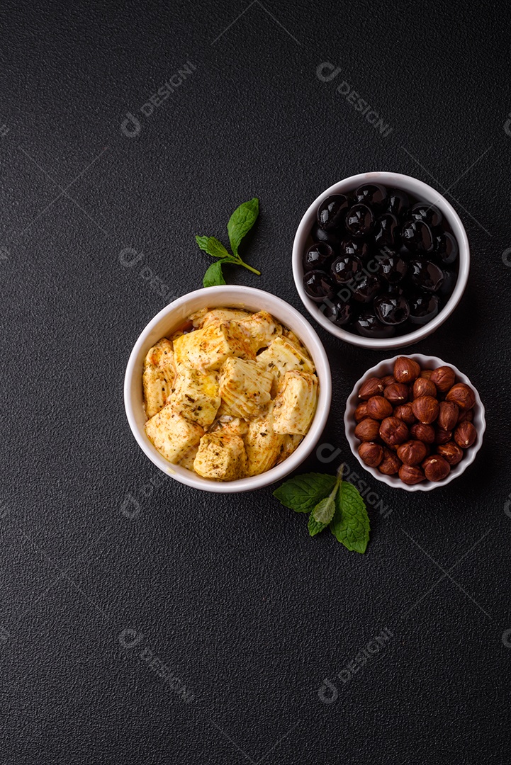 Delicioso queijo feta branco macio com sal, especiarias e ervas sobre um fundo escuro de concreto. Ingredientes para pratos mediterrâneos