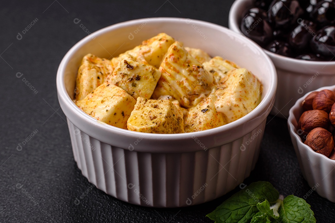 Delicioso queijo feta branco macio com sal, especiarias e ervas sobre um fundo escuro de concreto. Ingredientes para pratos mediterrâneos