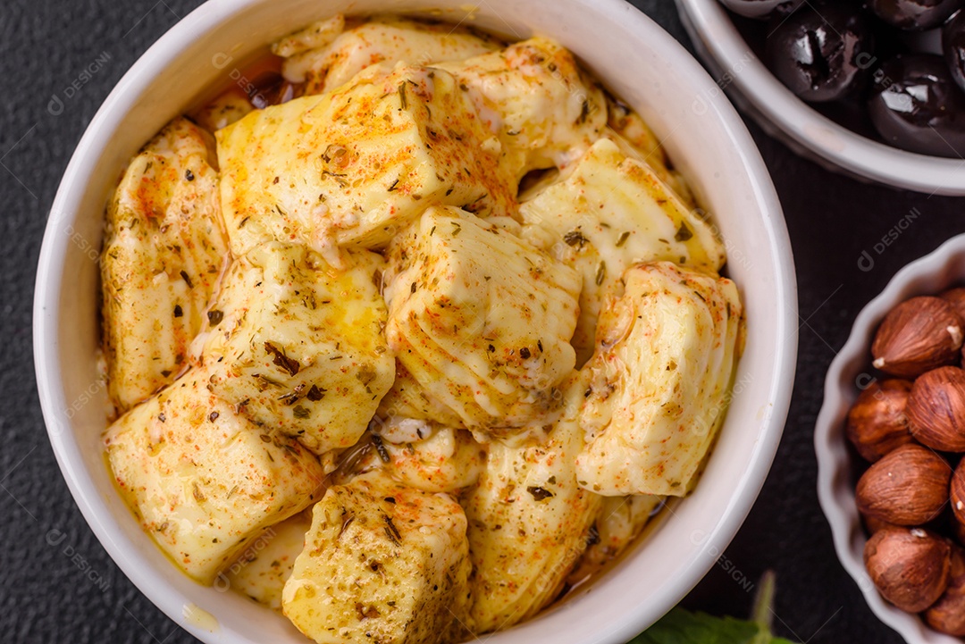 Delicioso queijo feta branco macio com sal, especiarias e ervas sobre um fundo escuro de concreto. Ingredientes para pratos mediterrâneos