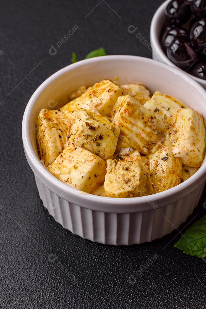 Delicioso queijo feta branco macio com sal, especiarias e ervas sobre um fundo escuro de concreto. Ingredientes para pratos mediterrâneos