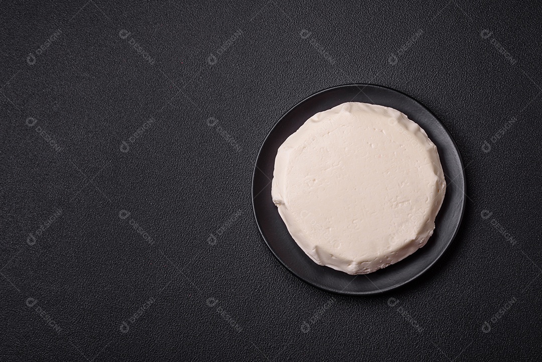 Delicioso queijo jovem branco fresco de leite de vaca ou ovelha sobre um fundo escuro de concreto