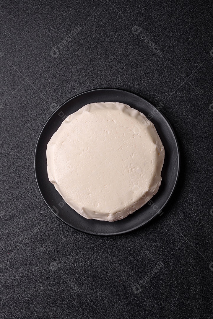 Delicioso queijo jovem branco fresco de leite de vaca ou ovelha sobre um fundo escuro de concreto