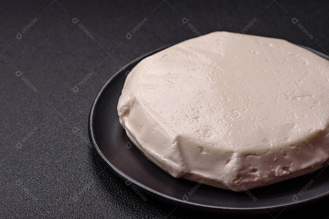 Delicioso queijo jovem branco fresco de leite de vaca ou ovelha sobre um fundo escuro de concreto