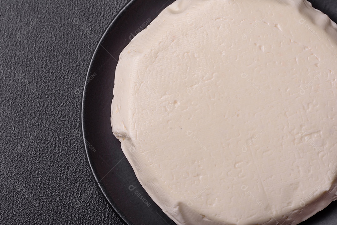 Delicioso queijo jovem branco fresco de leite de vaca ou ovelha sobre um fundo escuro de concreto