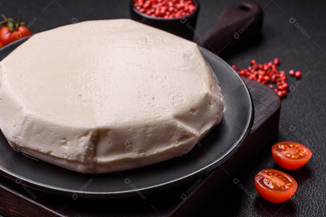 Delicioso queijo jovem branco fresco de leite de vaca ou ovelha sobre um fundo escuro de concreto