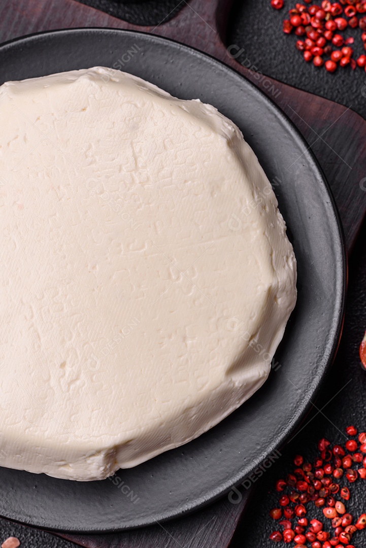 Delicioso queijo jovem branco fresco de leite de vaca ou ovelha sobre um fundo escuro de concreto