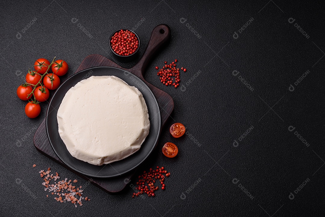 Delicioso queijo jovem branco fresco de leite de vaca ou ovelha sobre um fundo escuro de concreto
