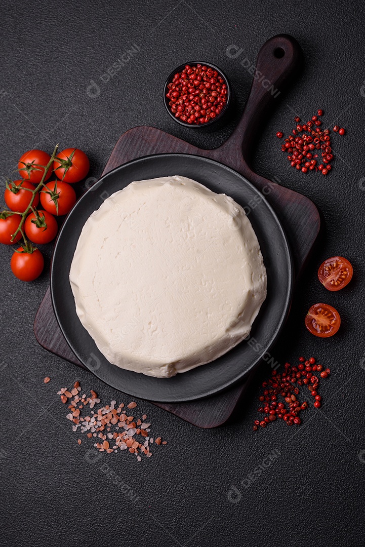 Delicioso queijo jovem branco fresco de leite de vaca ou ovelha sobre um fundo escuro de concreto