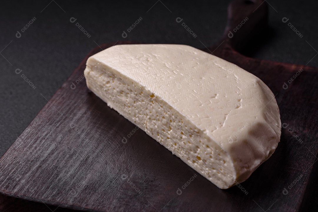 Delicioso queijo jovem branco fresco de leite de vaca ou ovelha sobre um fundo escuro de concreto
