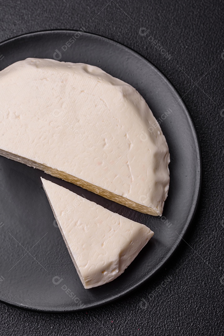 Delicioso queijo jovem branco fresco de leite de vaca ou ovelha sobre um fundo escuro de concreto