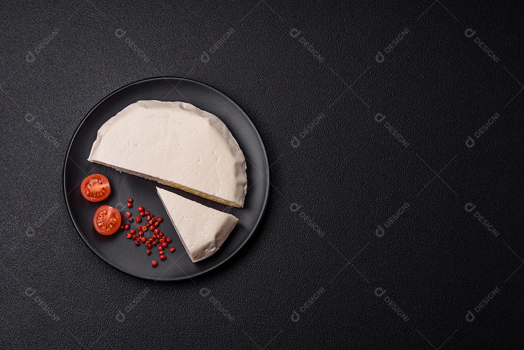 Delicioso queijo jovem branco fresco de leite de vaca ou ovelha sobre um fundo escuro de concreto