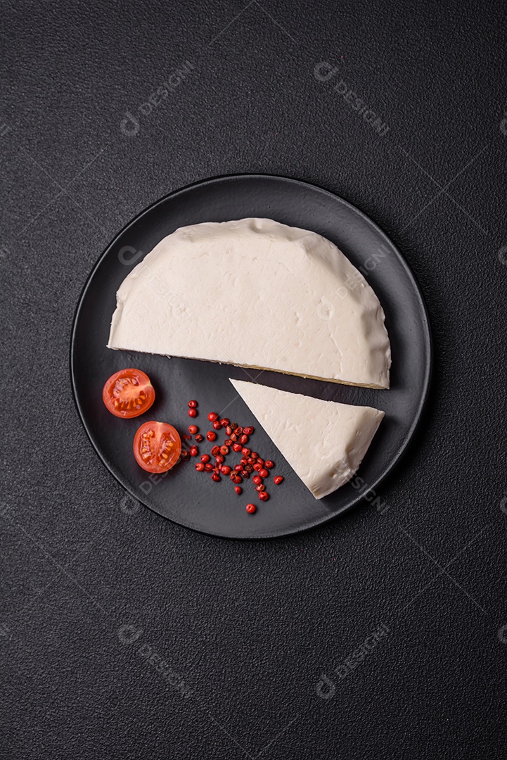 Delicioso queijo jovem branco fresco de leite de vaca ou ovelha sobre um fundo escuro de concreto