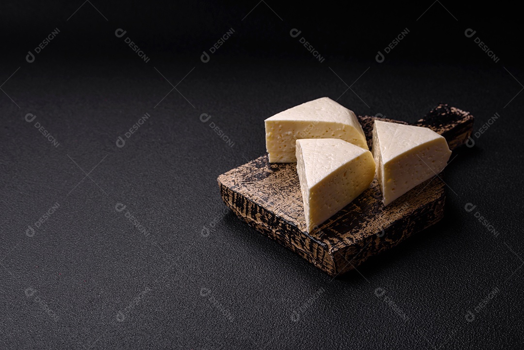 Delicioso queijo jovem branco fresco de leite de vaca ou ovelha sobre um fundo escuro de concreto