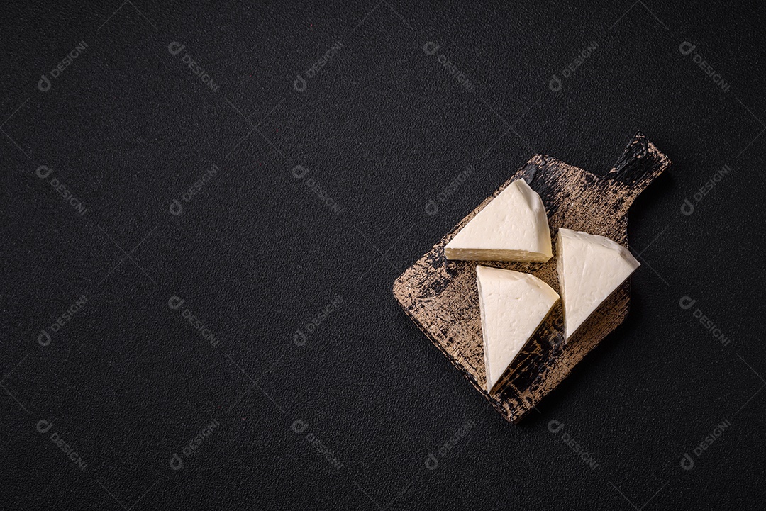 Delicioso queijo jovem branco fresco de leite de vaca ou ovelha sobre um fundo escuro de concreto