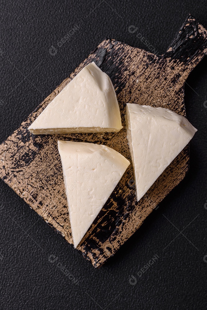 Delicioso queijo jovem branco fresco de leite de vaca ou ovelha sobre um fundo escuro de concreto