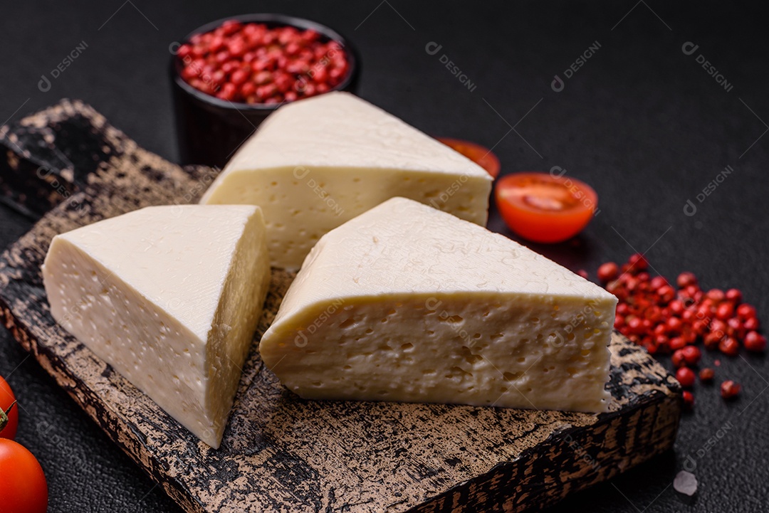 Delicioso queijo jovem branco fresco de leite de vaca ou ovelha sobre um fundo escuro de concreto