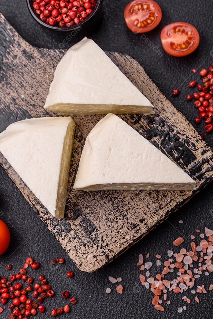 Delicioso queijo jovem branco fresco de leite de vaca ou ovelha sobre um fundo escuro de concreto