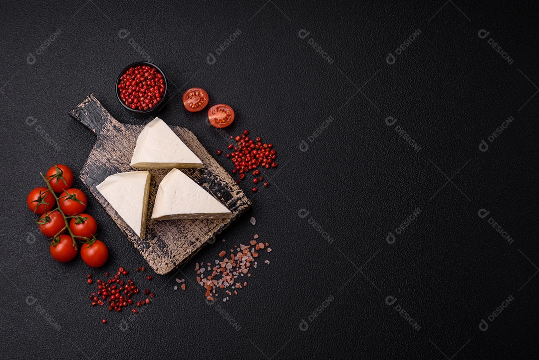 Delicioso queijo jovem branco fresco de leite de vaca ou ovelha sobre um fundo escuro de concreto