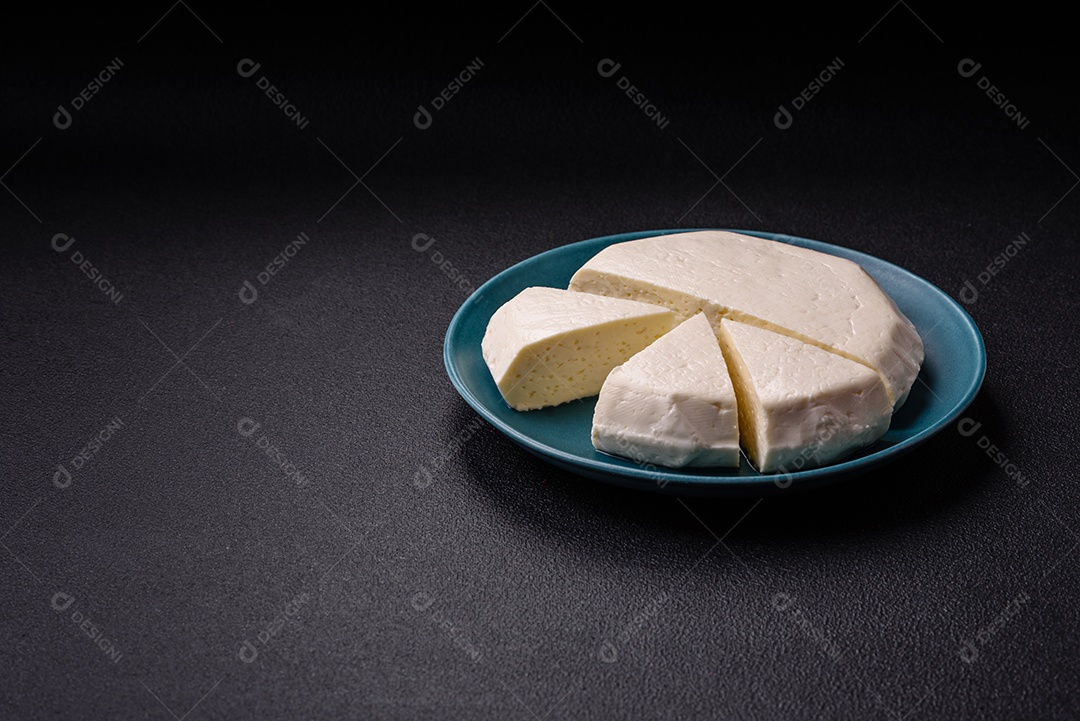 Delicioso queijo jovem branco fresco de leite de vaca ou ovelha sobre um fundo escuro de concreto