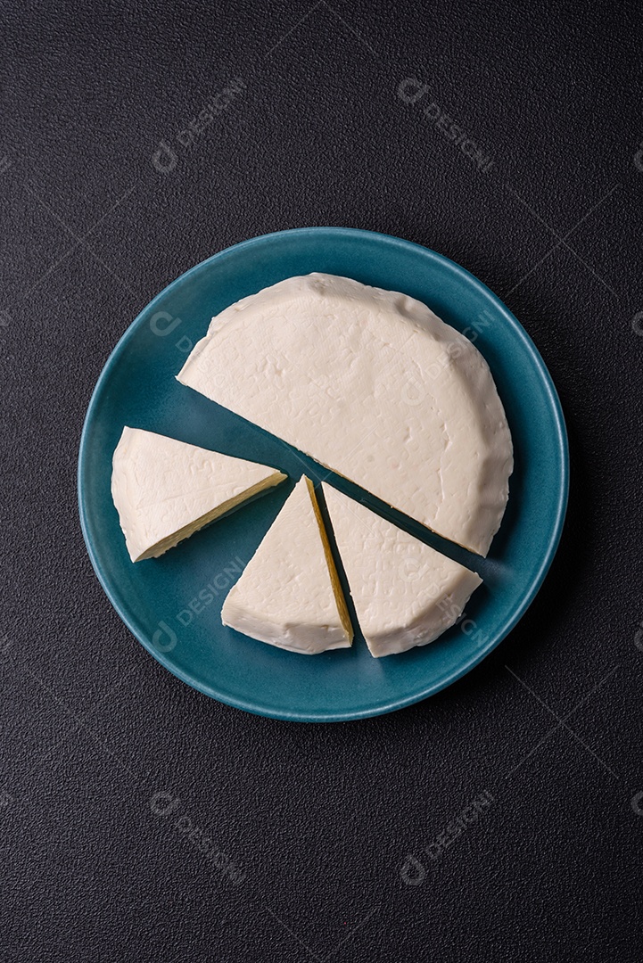 Delicioso queijo jovem branco fresco de leite de vaca ou ovelha sobre um fundo escuro de concreto