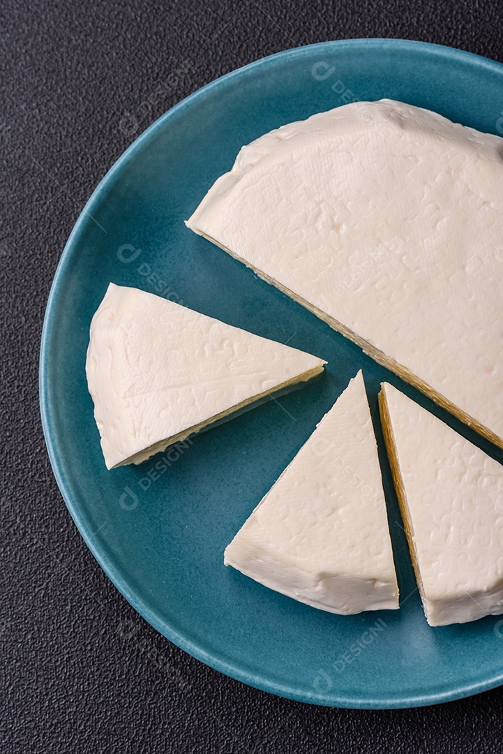Delicioso queijo jovem branco fresco de leite de vaca ou ovelha sobre um fundo escuro de concreto