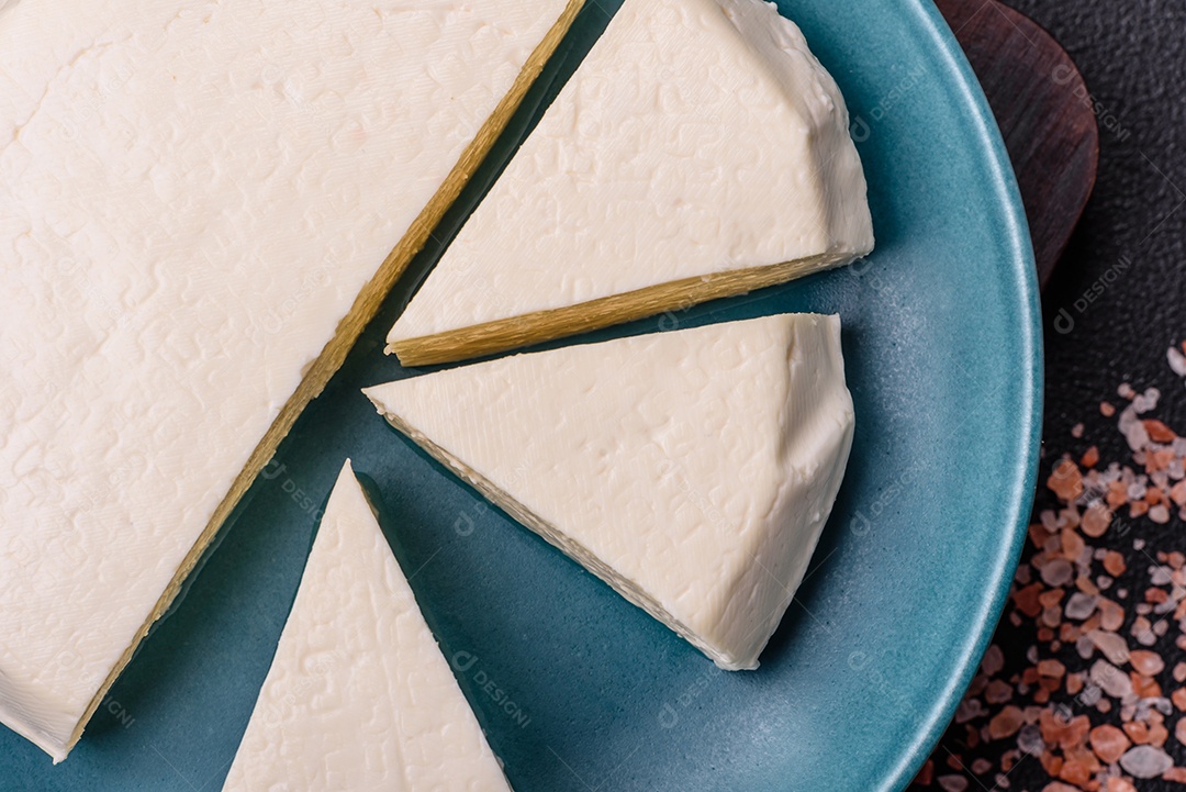 Delicioso queijo jovem branco fresco de leite de vaca ou ovelha sobre um fundo escuro de concreto