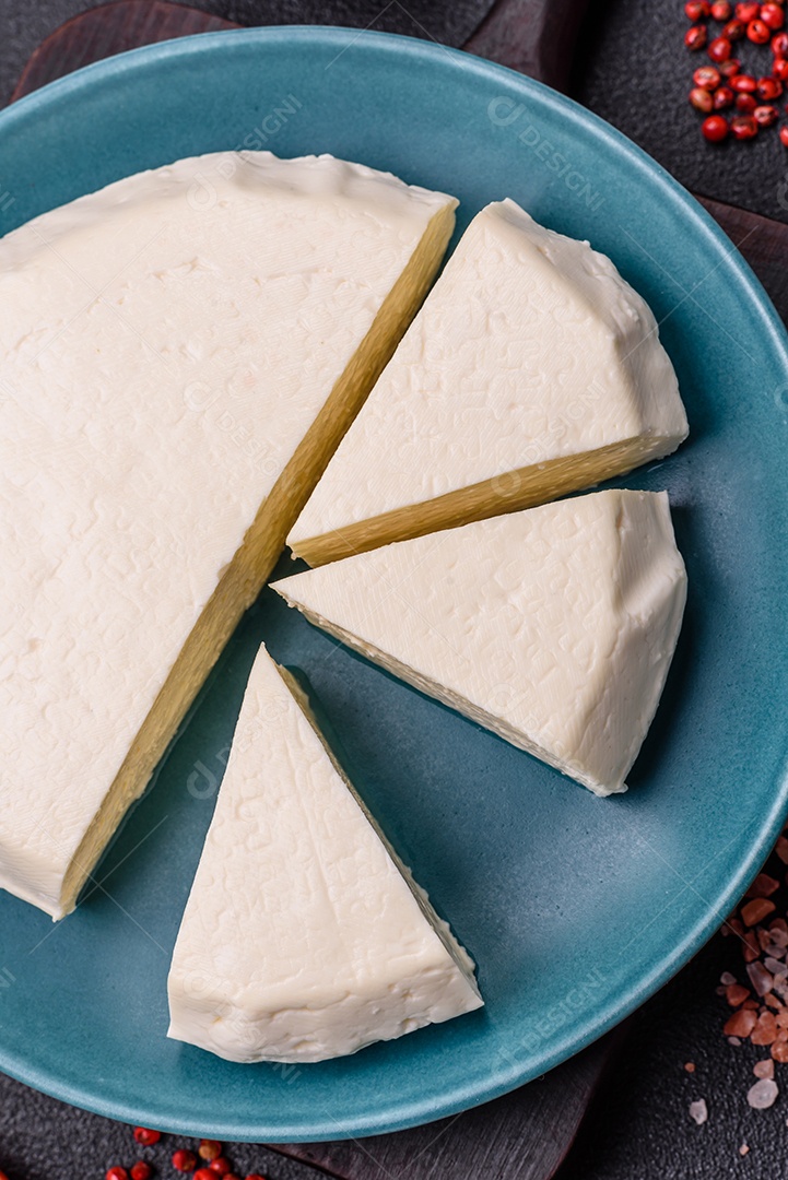 Delicioso queijo jovem branco fresco de leite de vaca ou ovelha sobre um fundo escuro de concreto