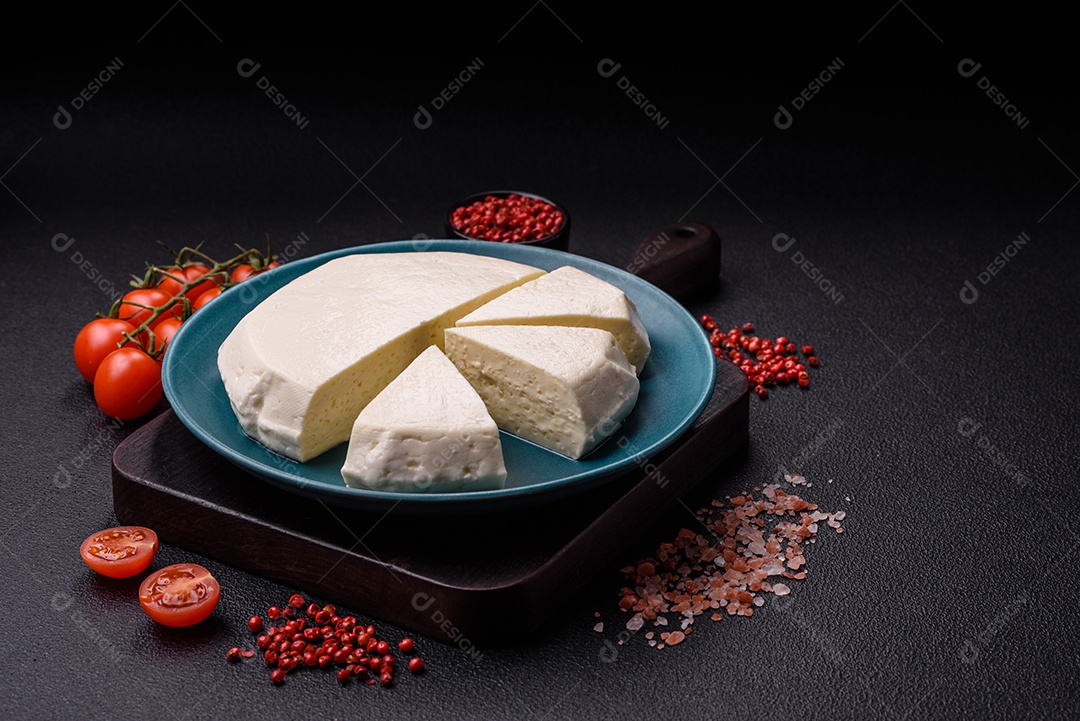 Delicioso queijo jovem branco fresco de leite de vaca ou ovelha sobre um fundo escuro de concreto