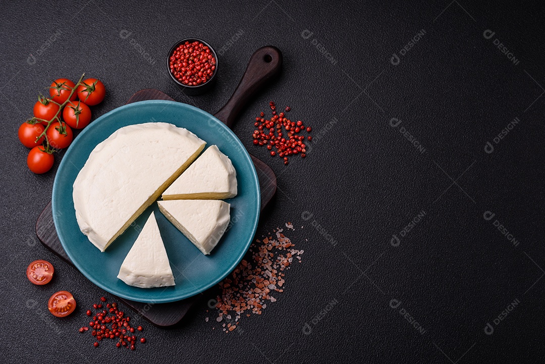 Delicioso queijo jovem branco fresco de leite de vaca ou ovelha sobre um fundo escuro de concreto