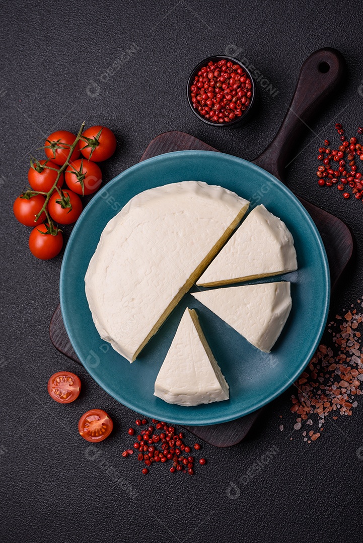 Delicioso queijo jovem branco fresco de leite de vaca ou ovelha sobre um fundo escuro de concreto