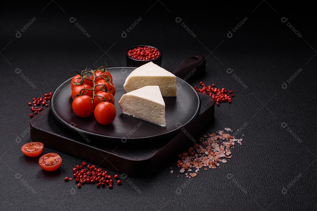 Delicioso queijo jovem branco fresco de leite de vaca ou ovelha sobre um fundo escuro de concreto