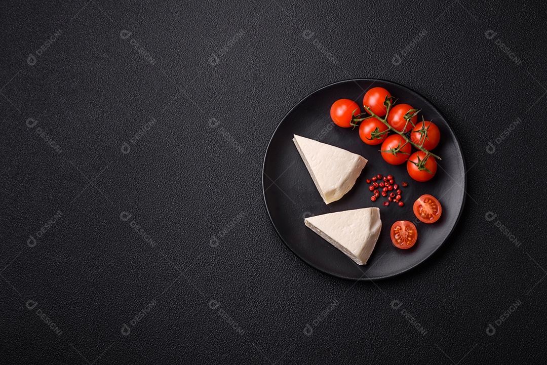 Delicioso queijo jovem branco fresco de leite de vaca ou ovelha sobre um fundo escuro de concreto